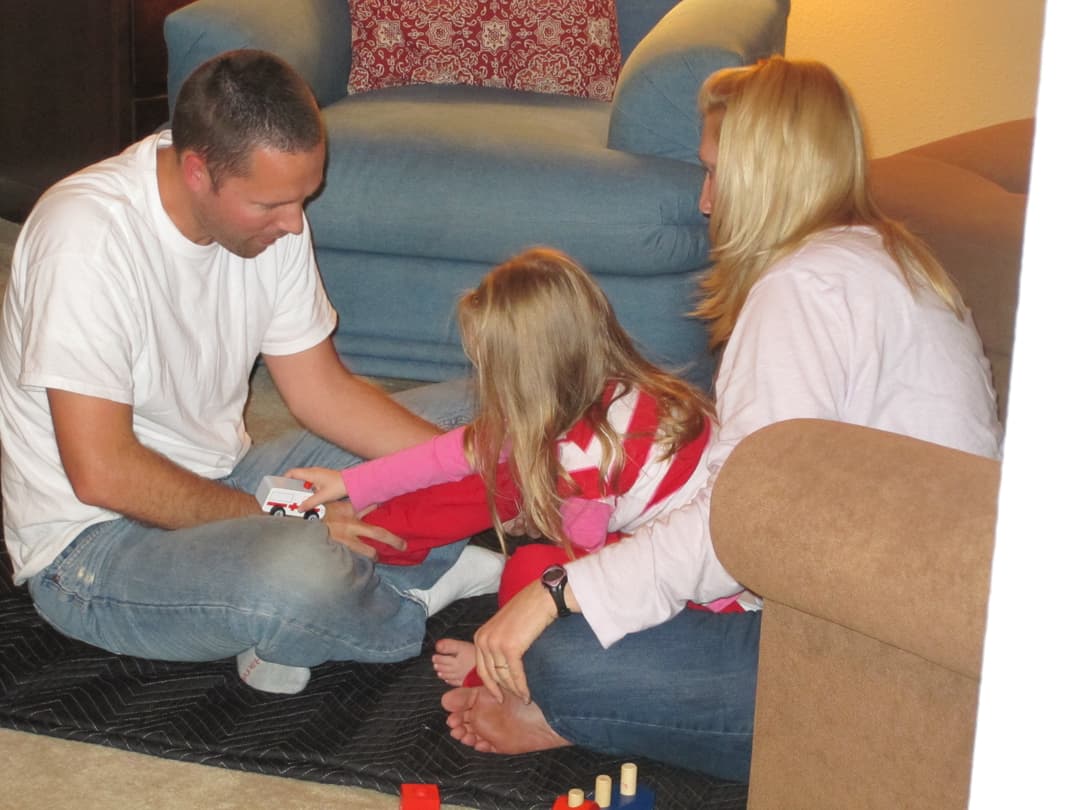 Child engaging with toys during a gentle NeuroMovement session with parents present